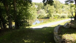 A grassy area with a stone wall and a pond. - Location Saisonnière en Bord de Loire (Coubon)
