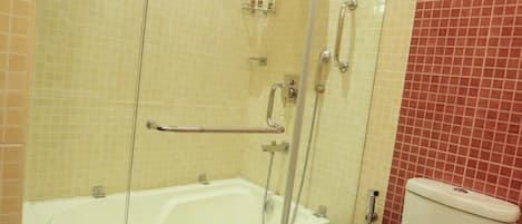 A bathroom with a glass-enclosed shower, a white bathtub, and a toilet.