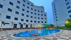 Un hotel con piscina, varios pisos y un diseño arquitectónico moderno.