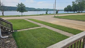 A residential area with a paved road, grassy areas, and a body of water in the background. - Charlie’s on the Water - a Charming 3-bedroom house with a lake view-Sabula (Sabula)