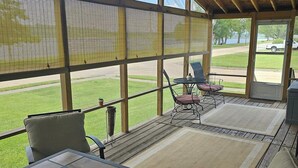 A covered patio area with a view of a grassy field and a lake. - Charlie’s on the Water - a Charming 3-bedroom house with a lake view-Sabula (Sabula)