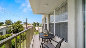 Ein Balkon mit einem Tisch für zwei Personen, einer Weinflasche und einer Obstplatte.