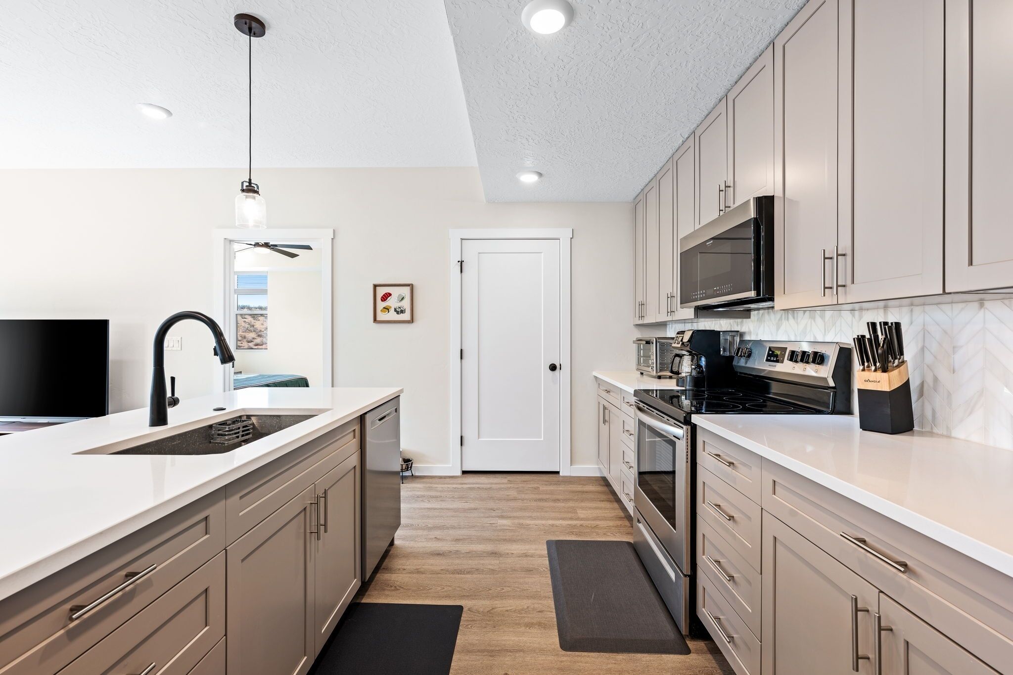 A modern kitchen with white cabinetry, stainless steel appliances, and a black countertop.