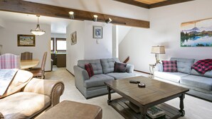 A living room with a grey sofa, a wooden coffee table, and a dining area with a table and chairs. - G3 Meadow Creek 3 Bedroom Townhouse by RedAwning (Vail)