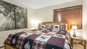 A bedroom with a large bed, a forest-themed wall art, a window with blinds, and bedside lamps. - G3 Meadow Creek 3 Bedroom Townhouse by RedAwning (Vail)