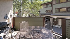 A patio with a round metal table and chairs, a grill, and a fence. - G3 Meadow Creek 3 Bedroom Townhouse by RedAwning (Vail)