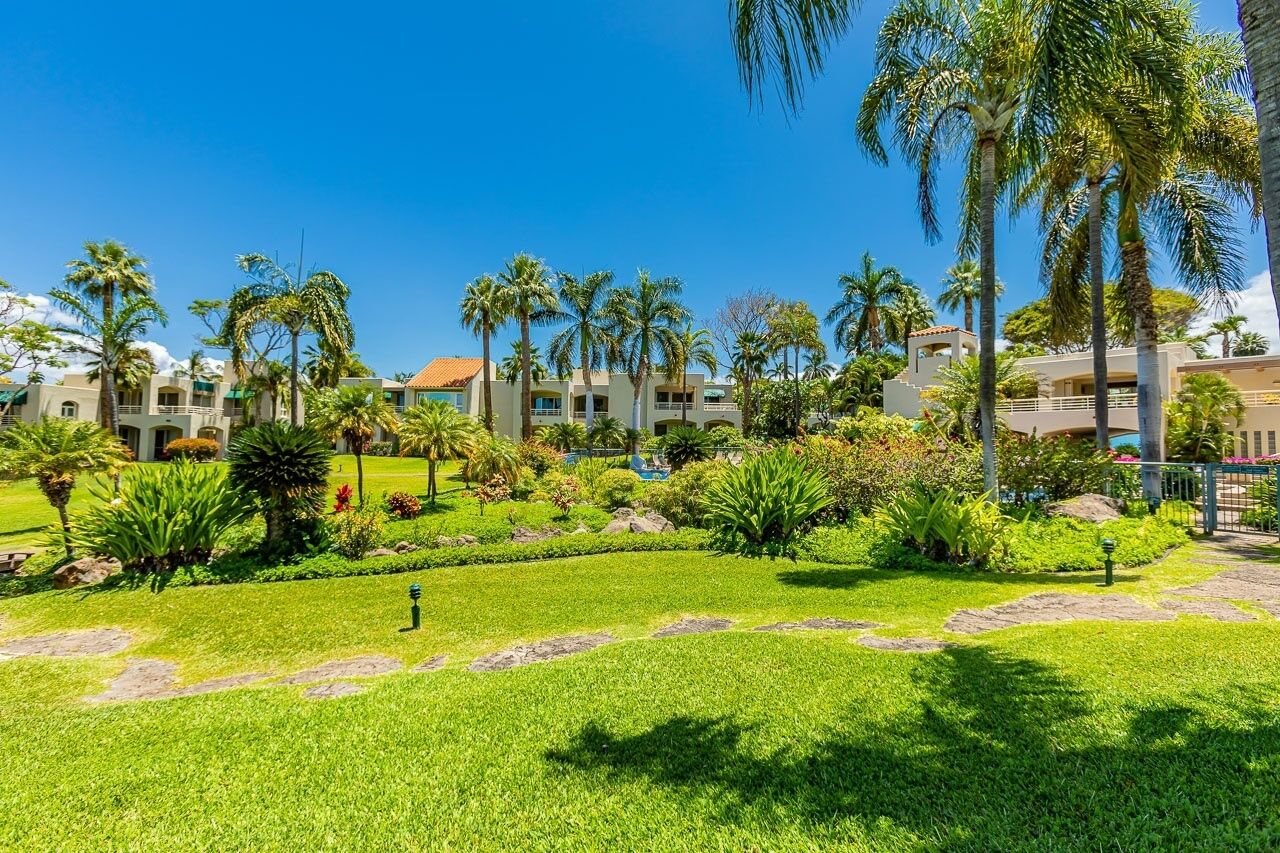 Un resort con un prato curato, palme e un edificio con diversi balconi.