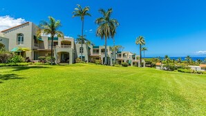 A large, multi-story building with a well-maintained lawn and several palm trees. - Palms At Wailea 2303 2 Bedroom Condo (Kihei)