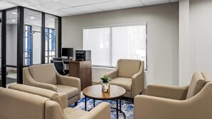 Una habitación de hotel moderna con un ventanal grande, un escritorio con computadora y asientos cómodos.
