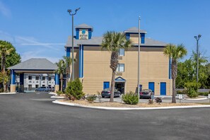 A hotel with a modern design, featuring a central entrance, a parking area, and a clear sky. - Jesup Inn & Suites (Jesup)
