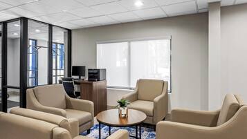 Una habitación de hotel moderna con un ventanal grande, un escritorio con computadora y asientos cómodos.