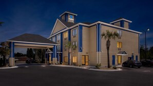 Un hotel Clarion Pointe con vestíbulo cubierto, múltiples ventanales y aparcamiento.