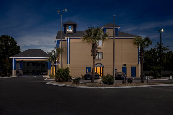 A hotel with a clear entrance, a parking lot, and a sign indicating it is a Clarion Pointe hotel.