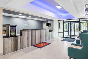 A reception area with a wooden reception desk, a glass door entrance, and a seating area with chairs.