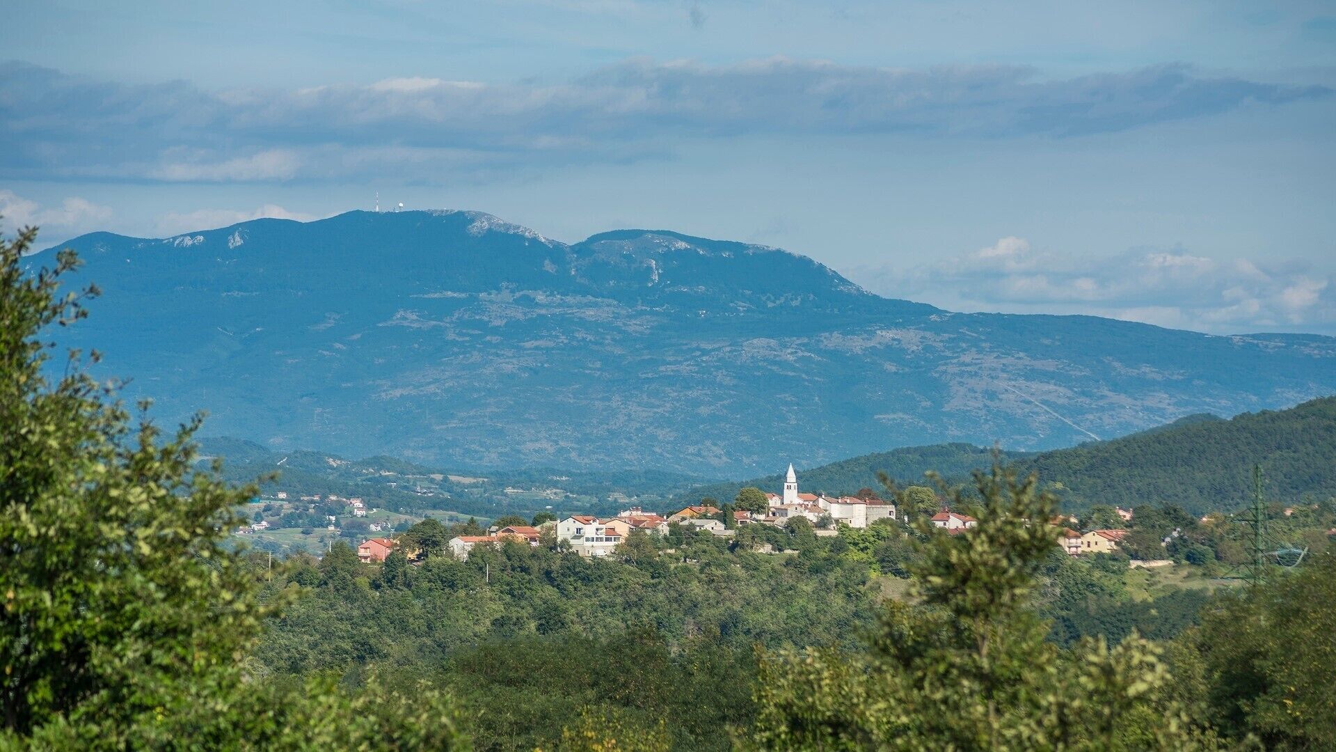 A town nestled in a valley with a prominent church and surrounding hills.