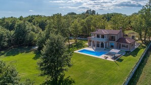 A large two-story house with a swimming pool, surrounded by a well-maintained lawn and trees. - Modern Villa Anima with swimming pool (Pazin)