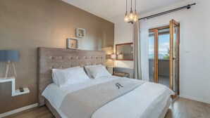 A bedroom with a large bed, a bedside table with a lamp, a mirror, and a view of the outdoors through a sliding door. - Modern Villa Anima with swimming pool (Pazin)