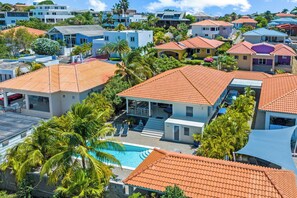 A residential area with multiple houses, a swimming pool, and palm trees. - Villa Noukasa, Brakkeput Abou, Lovely family home fully equipped with private pool, max 6 pers (Jan Thiel)