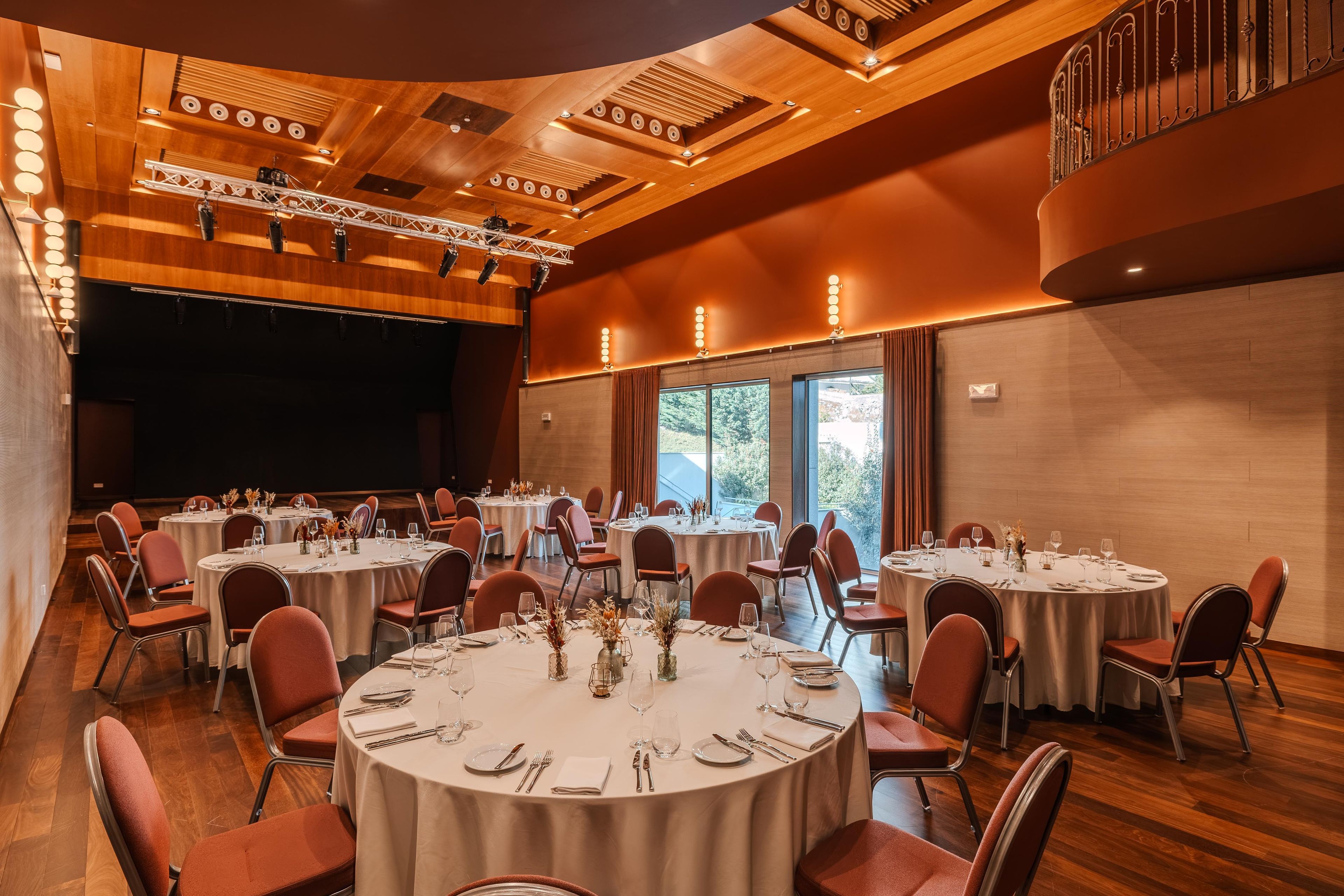 Un salón de conferencias con varias mesas redondas, sillas y una zona de escenario.