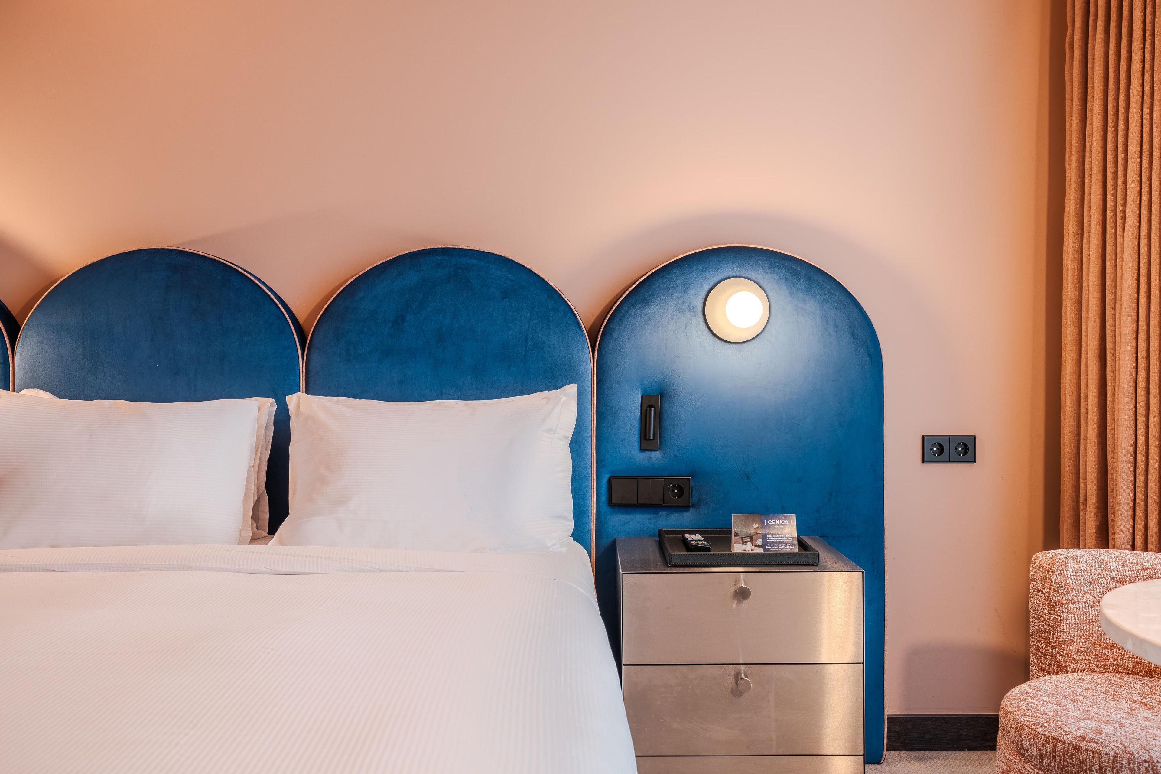 Una habitación de hotel con una cama, una mesita de noche, una lámpara y una silla.