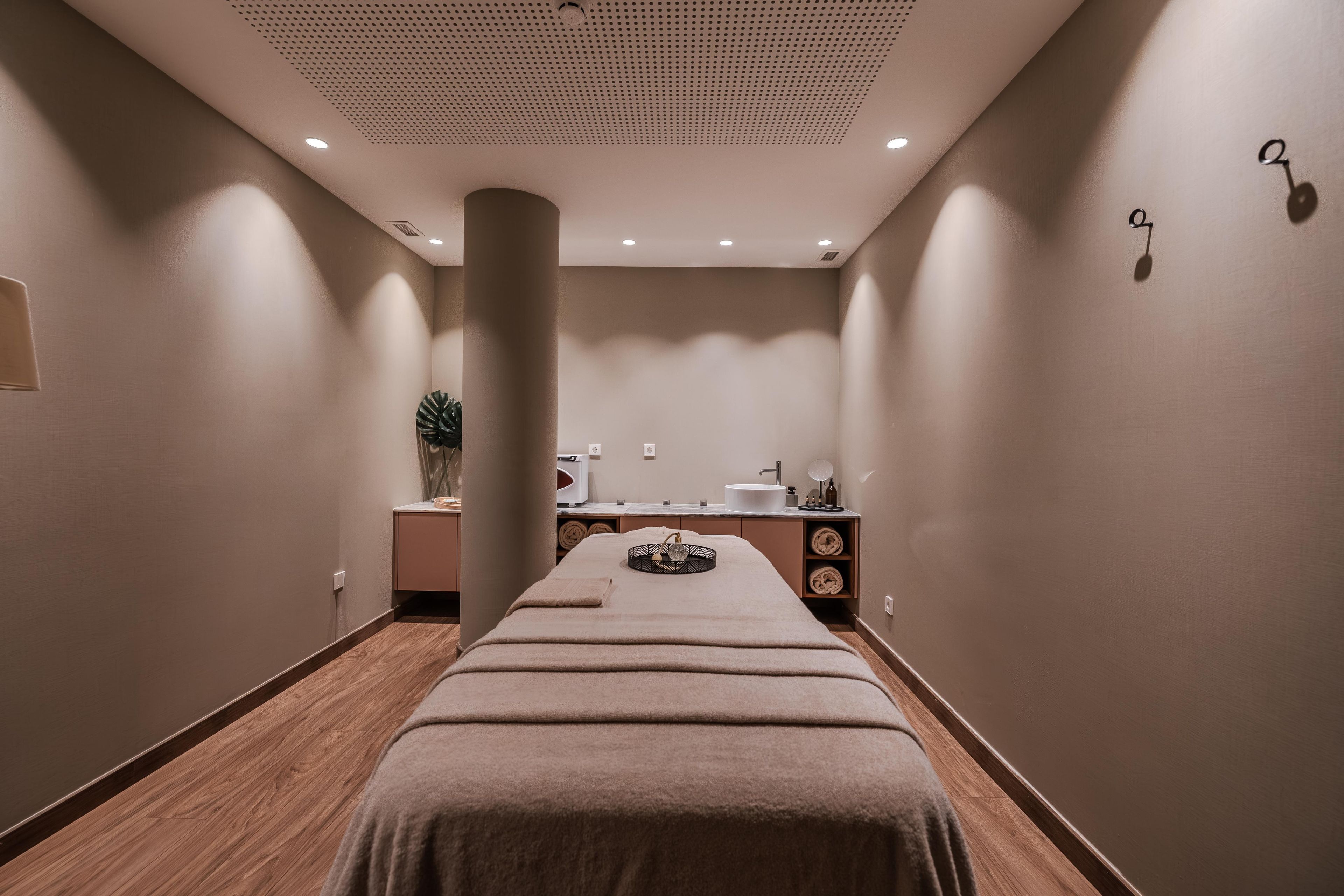 Een spa-ruimte met een massagetafel, een wastafel en een spiegel.