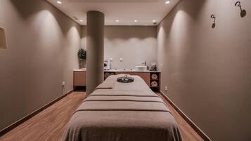 Een spa-ruimte met een massagetafel, een wastafel en een spiegel.