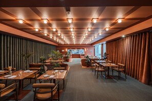 A restaurant with multiple dining tables and booths, a ceiling with recessed lighting, and a view of the street through large windows. - Cenica Porto Hotel, Curio Collection by Hilton (Porto)