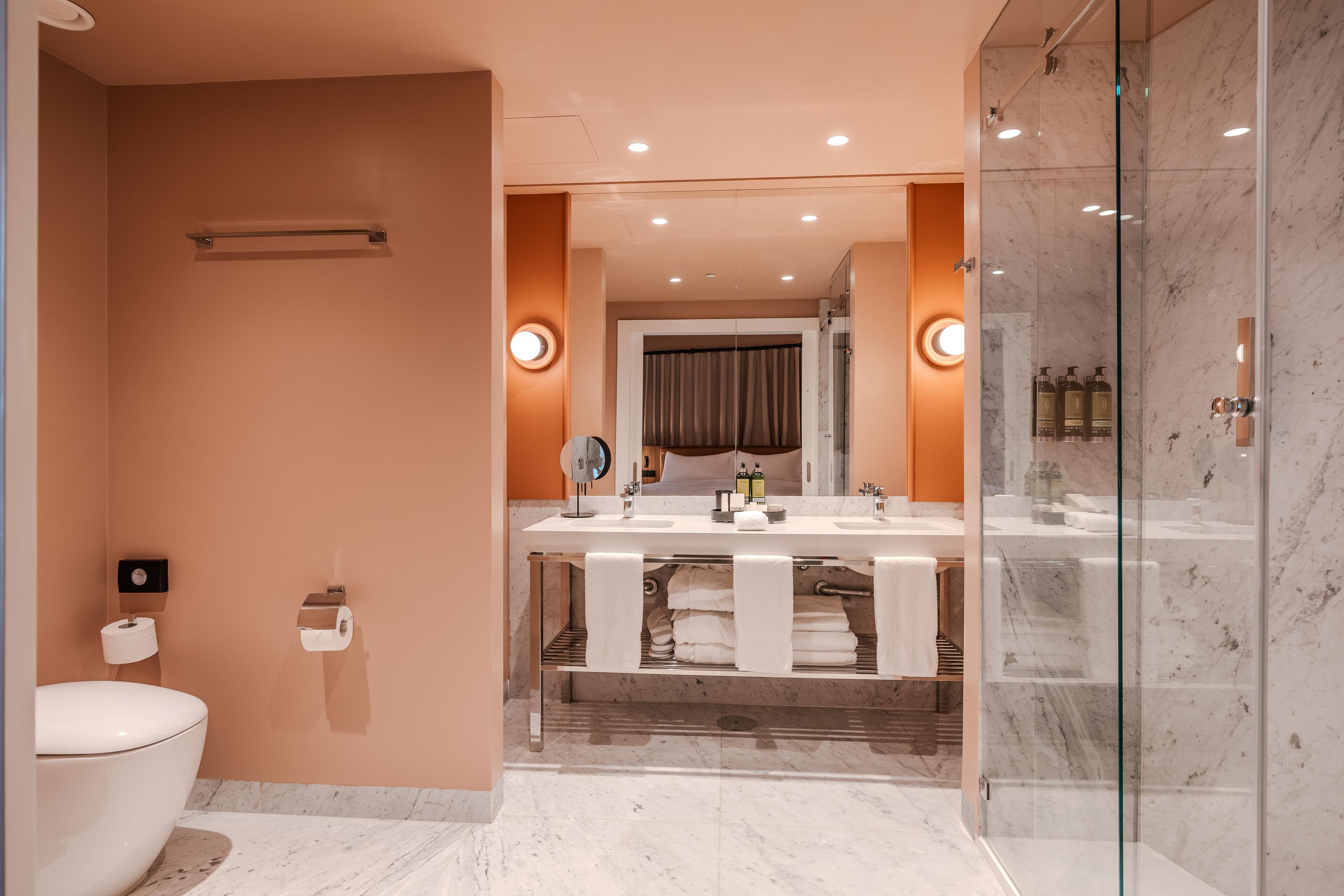 Un baño moderno con cabina de ducha de vidrio, inodoro y tocador con espejo.