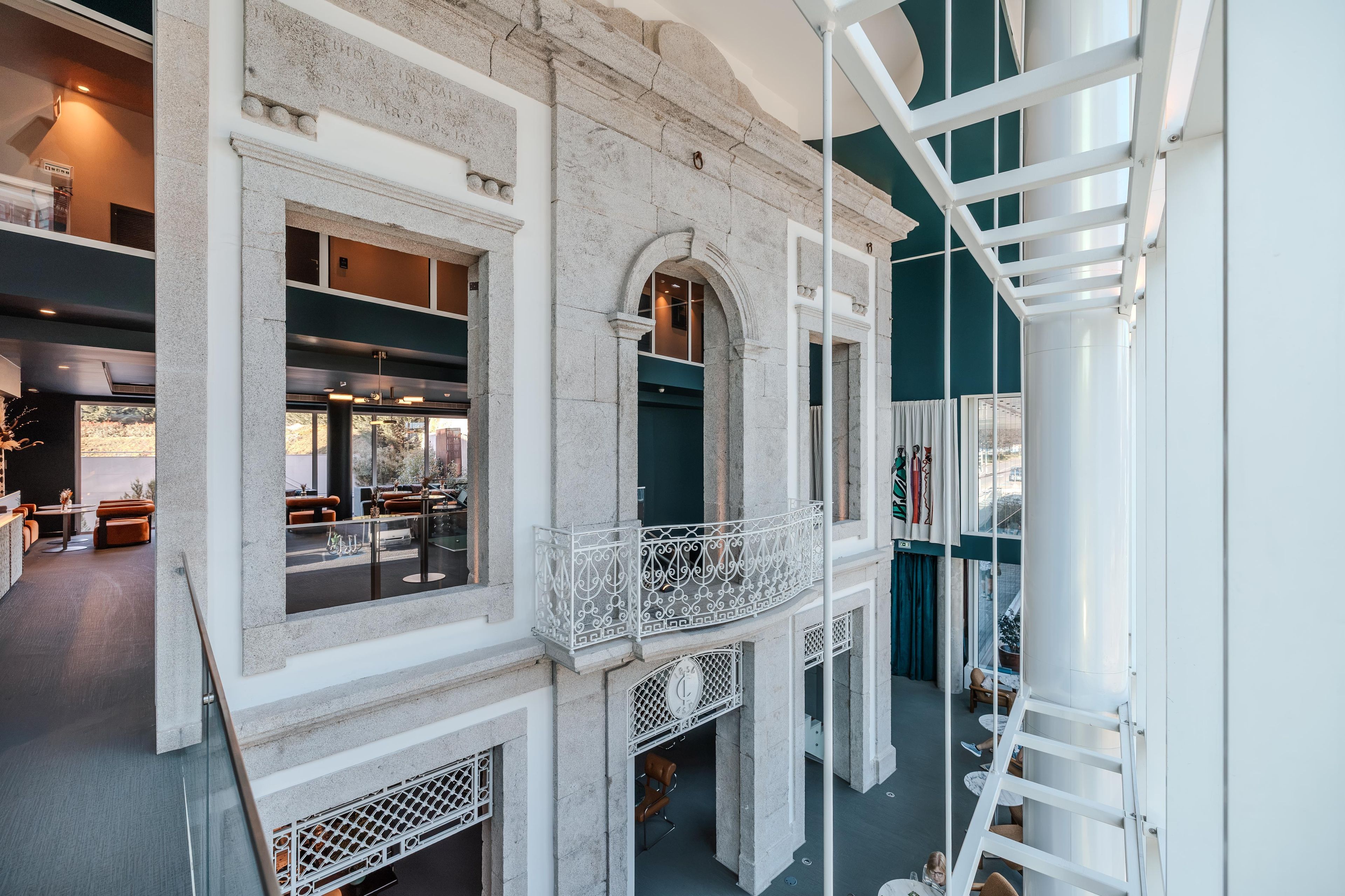 Un intérieur moderne avec une façade en pierre, un balcon agrémenté de balustrades en métal ouvragé et une vue sur la rue en contrebas.
