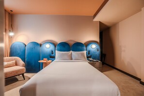 A hotel room with a large bed, a seating area with a chair, a small table, and a wall-mounted phone. - Cenica Porto Hotel, Curio Collection by Hilton (Porto)