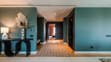 A hallway with a tiled floor, a desk with a lamp, and a decorative vase.