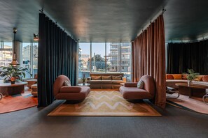 Ein modernes Wohnzimmer mit großem Fenster, einer Couch, zwei Sesseln und einem Couchtisch.