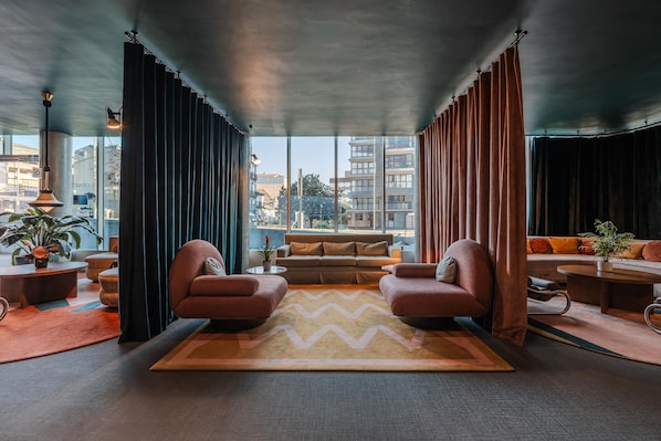 A modern living room with a large window, a sofa, two armchairs, and a coffee table.