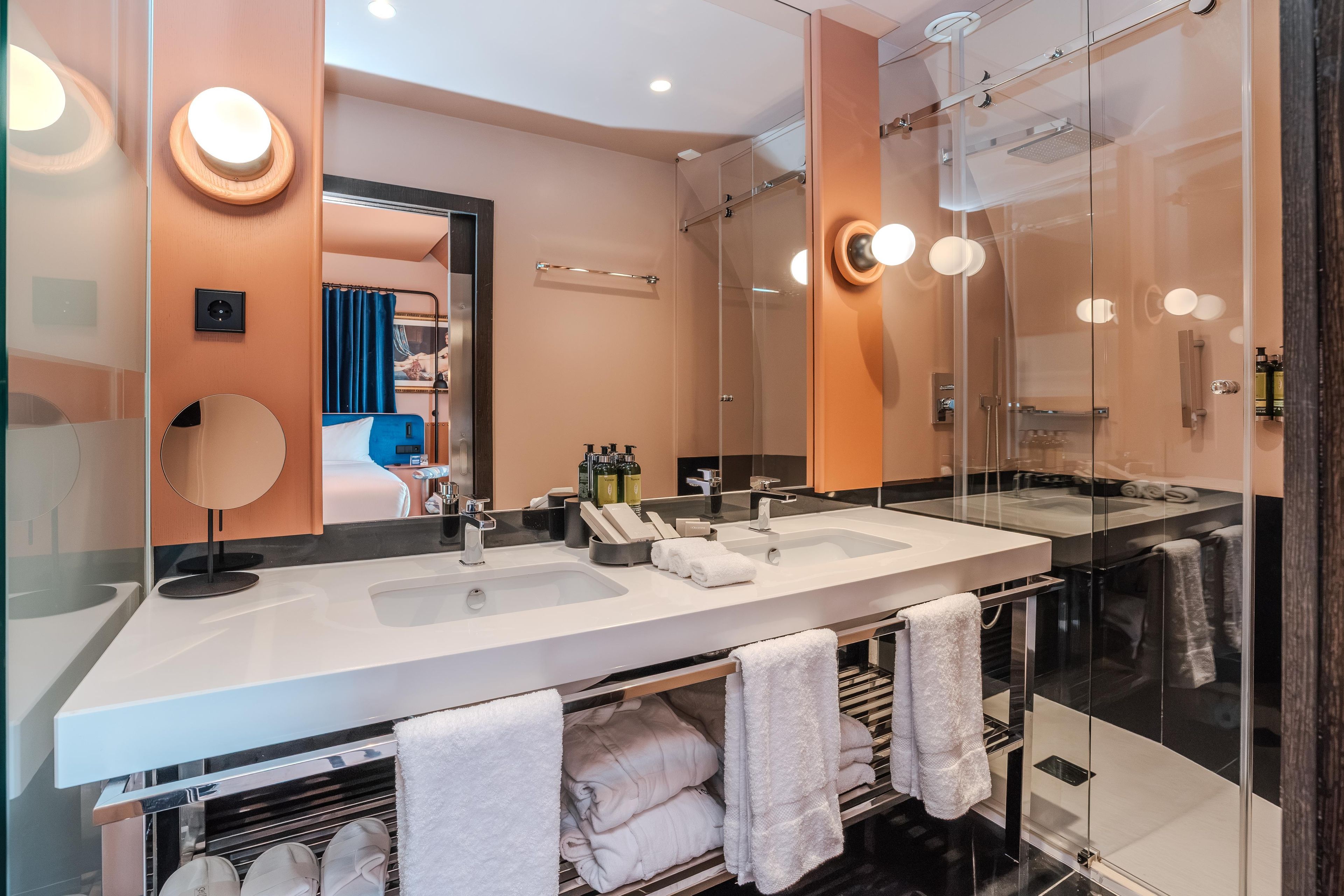 Une salle de bain moderne avec deux vasques, une douche à l’italienne et un grand miroir.