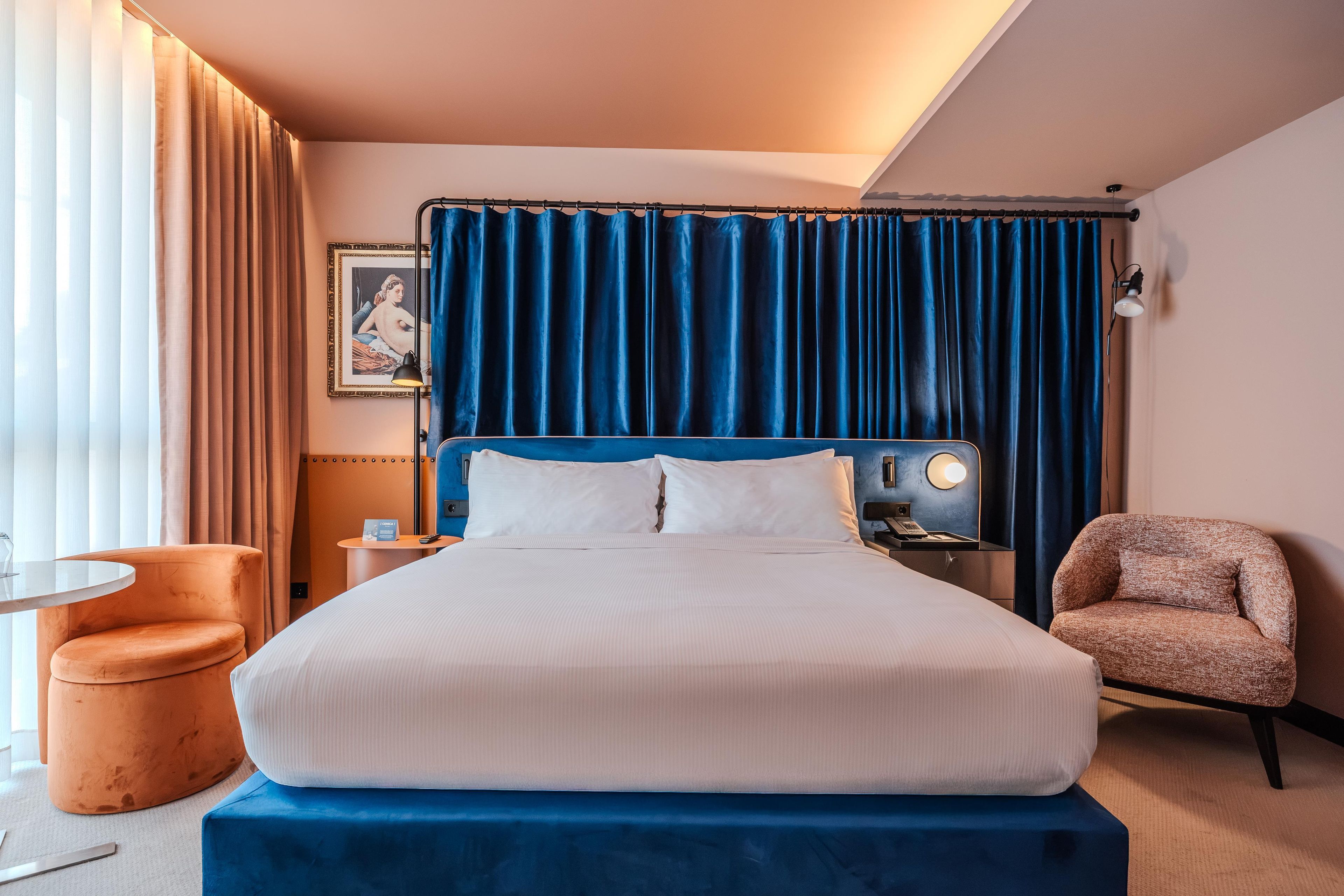 A hotel room with a large bed, a chair, a desk, and a view of the outdoors.