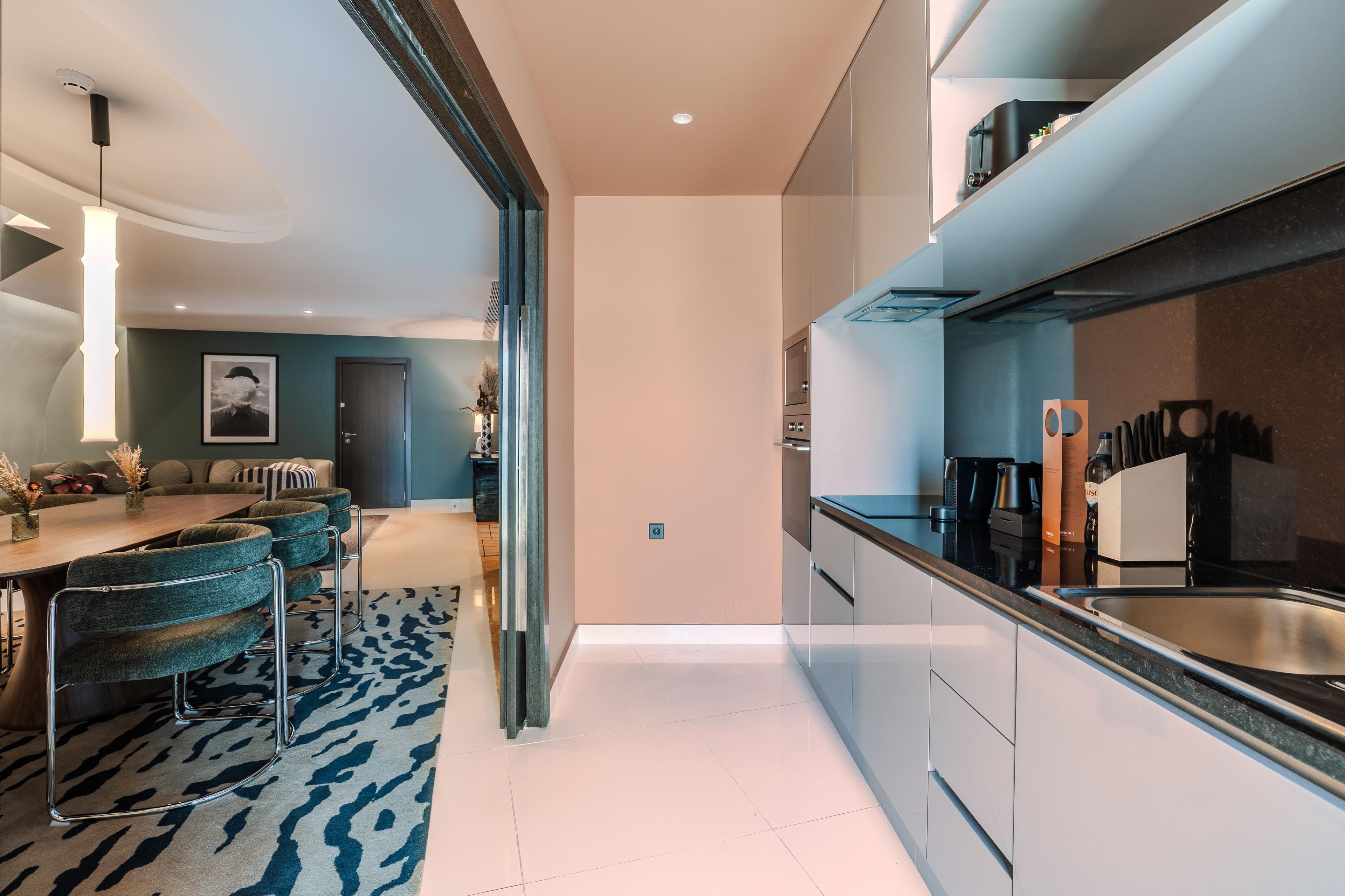 A modern kitchen with a stainless steel sink, a coffee machine, and a refrigerator.