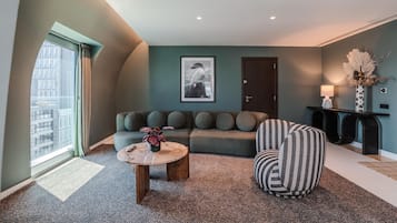A modern living room with a sofa, a round coffee table, and a striped armchair.