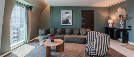A modern living room with a sofa, a round coffee table, and a striped armchair.