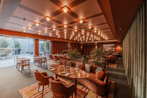 Un amplio vestíbulo de hotel con varias zonas de estar, un ventanal que ofrece vistas al exterior y un diseño de techo moderno con iluminación empotrada.