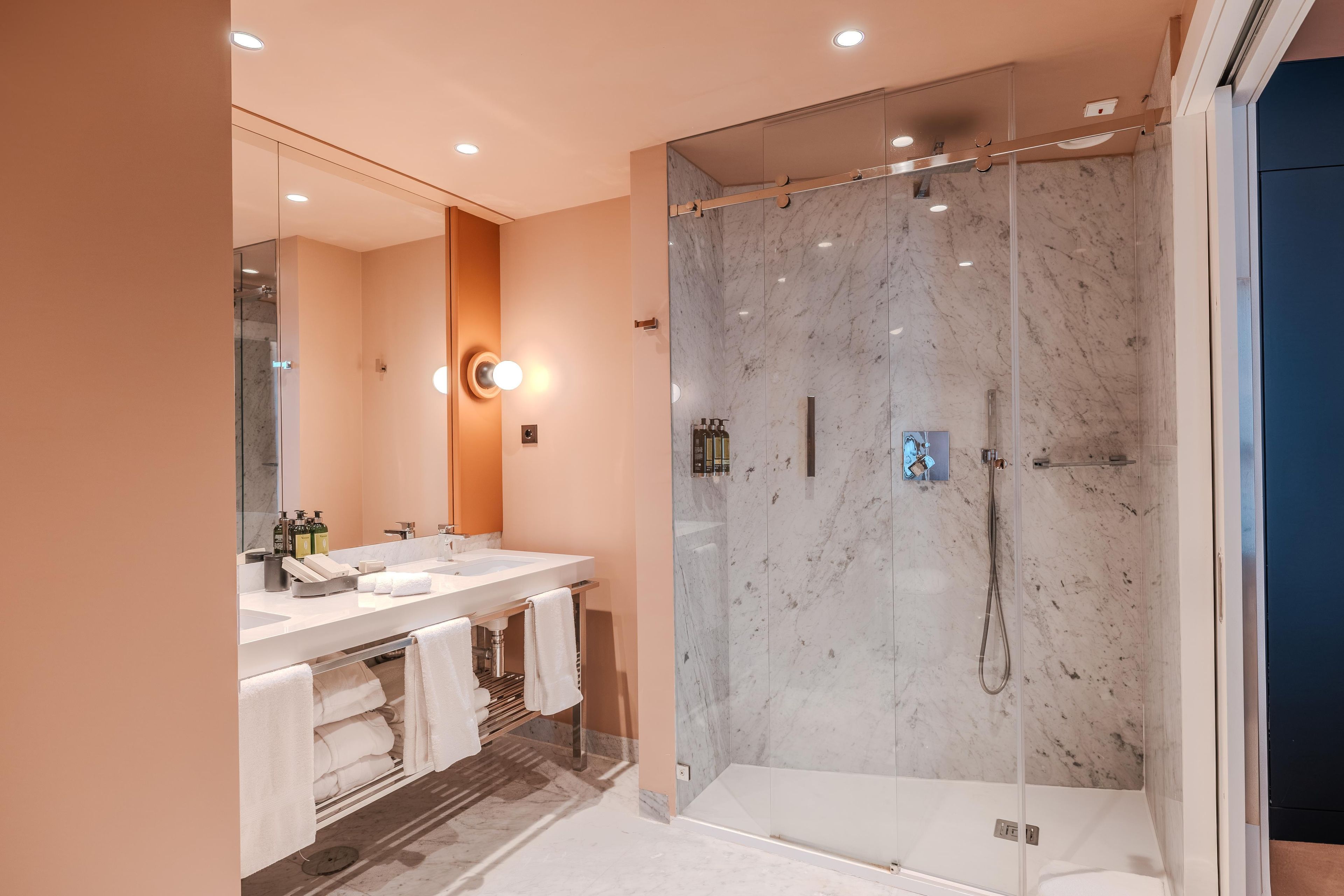 Un baño moderno con cabina de ducha de vidrio, tocador con un espejo grande y bañera.