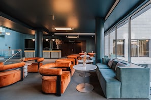 A modern lounge area with seating arrangements, a bar, and large windows. - Cenica Porto Hotel, Curio Collection by Hilton (Porto)