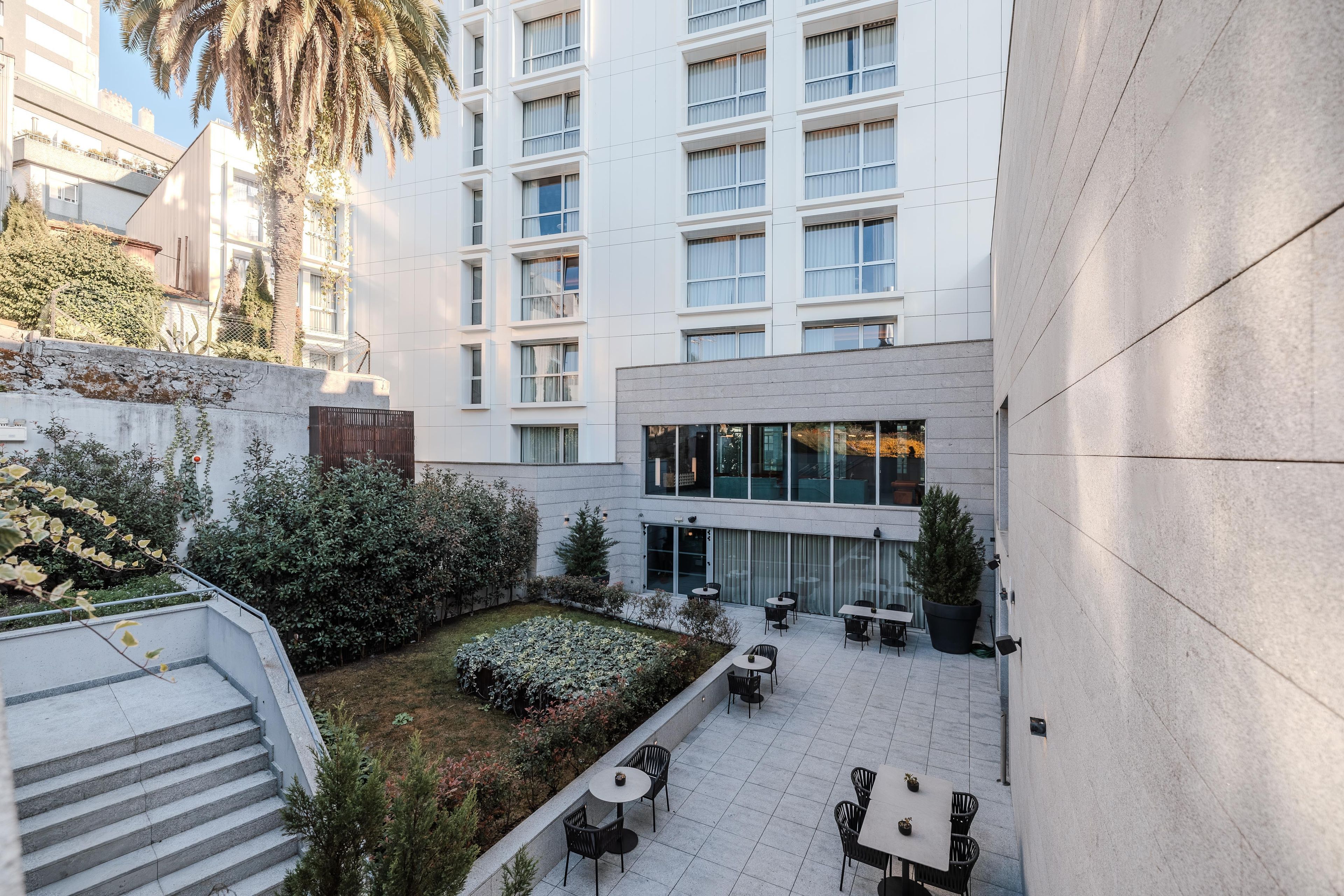 Un patio con mobiliario exterior, una escalera y un edificio con varias ventanas.