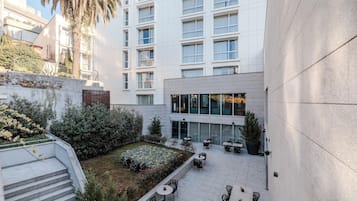 Un patio con mobiliario exterior, una escalera y un edificio con varias ventanas.