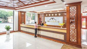 Zona de recepción de un hotel con diseño moderno, que incluye un mostrador, un ventanal grande y un panel decorativo de madera.