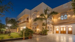 Un edificio tradicional con arcos ornamentados y un patio con plantas en macetas.