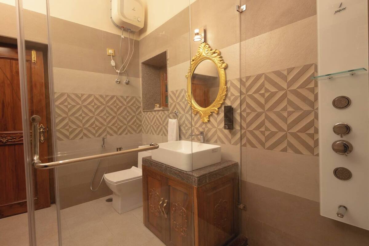 A bathroom with a glass shower enclosure, a white sink, and a vanity with a mirror.
