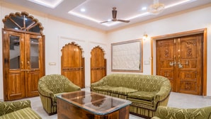 Una habitación con un conjunto de sofá, una mesa de centro y puertas de madera con diseños elaborados.