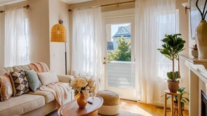 A living room with a sofa, a coffee table with a vase, a floor lamp, and a view through a door. - Spacious 3B/2.5B Home in the Heart of Capitol Hill (Seattle)