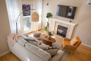 A living room with a sofa, armchair, round coffee table, and a fireplace.