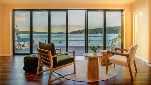 A spacious room with a large sliding glass door leading to a balcony overlooking a lake. - 1BR 2BA Lower Unit with Lake Access - Prime Spot (Issaquah)